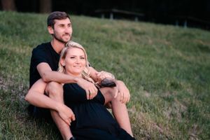 Couple relaxing on grassy hillside during outdoor portrait session.