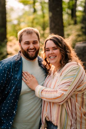 Happy couple sharing a candid moment in forest setting during engagement photoshoot.