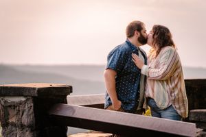 A romantic couple sharing an intimate moment on a bench at sunset.