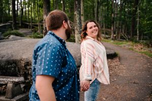 A couple walks along a forest trail enjoying a casual outdoor adventure.