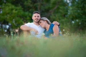 A tender moment shared between two people sitting in tall grass during golden hour.