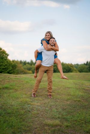 A playful piggyback ride moment captured in a grassy field during golden hour.