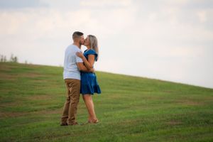 A romantic embrace captured on a serene hillside during sunset.