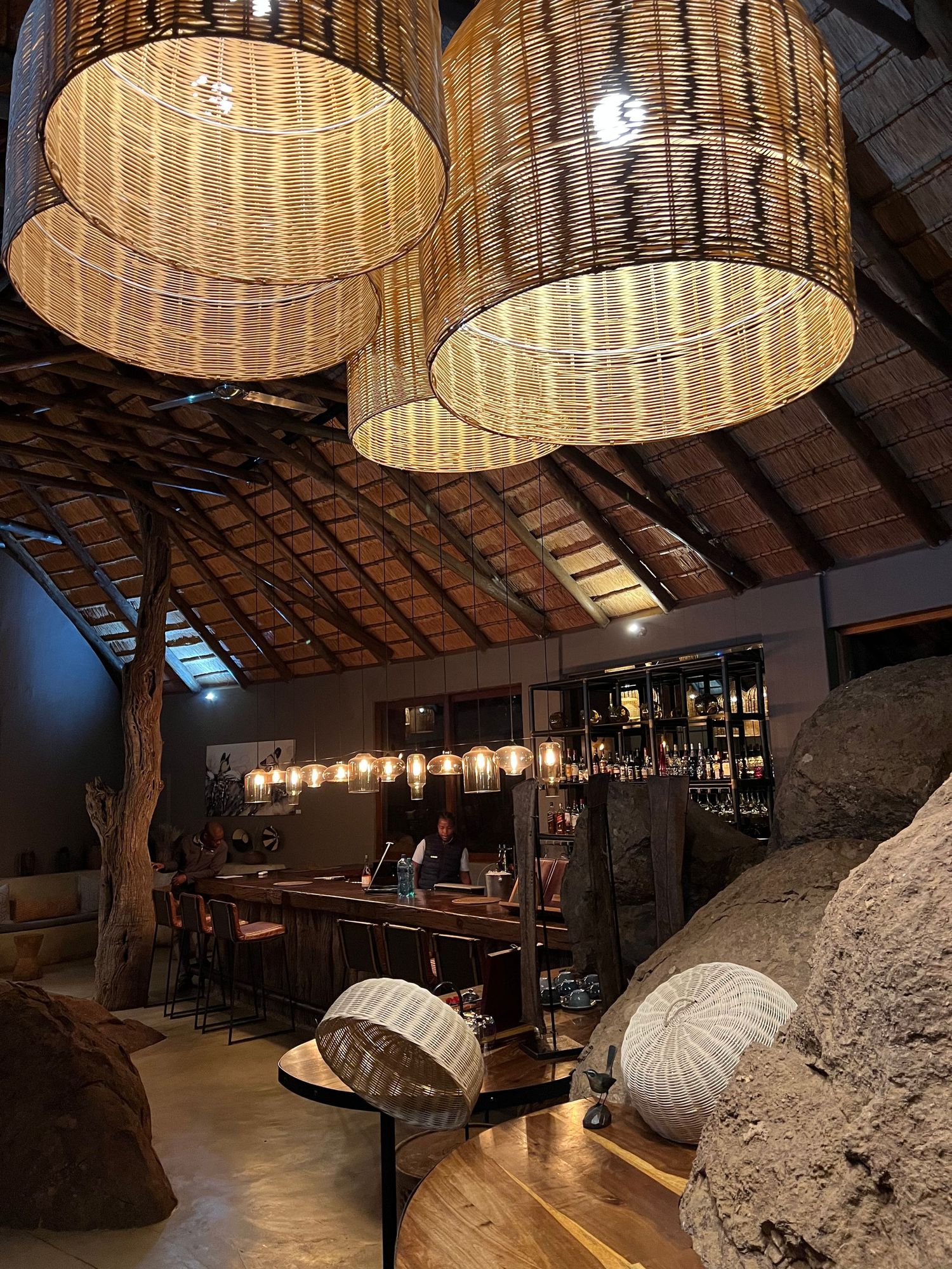 Rustic lodge interior with woven basket pendant lights and thatched roof design.