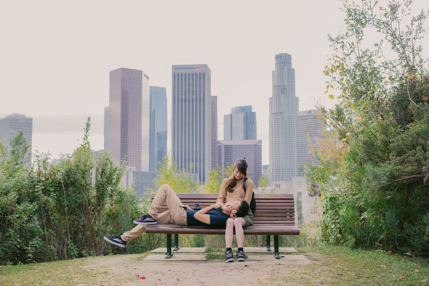 Panoramic view of Los Angeles skyline with green park in the foreground during sunset.