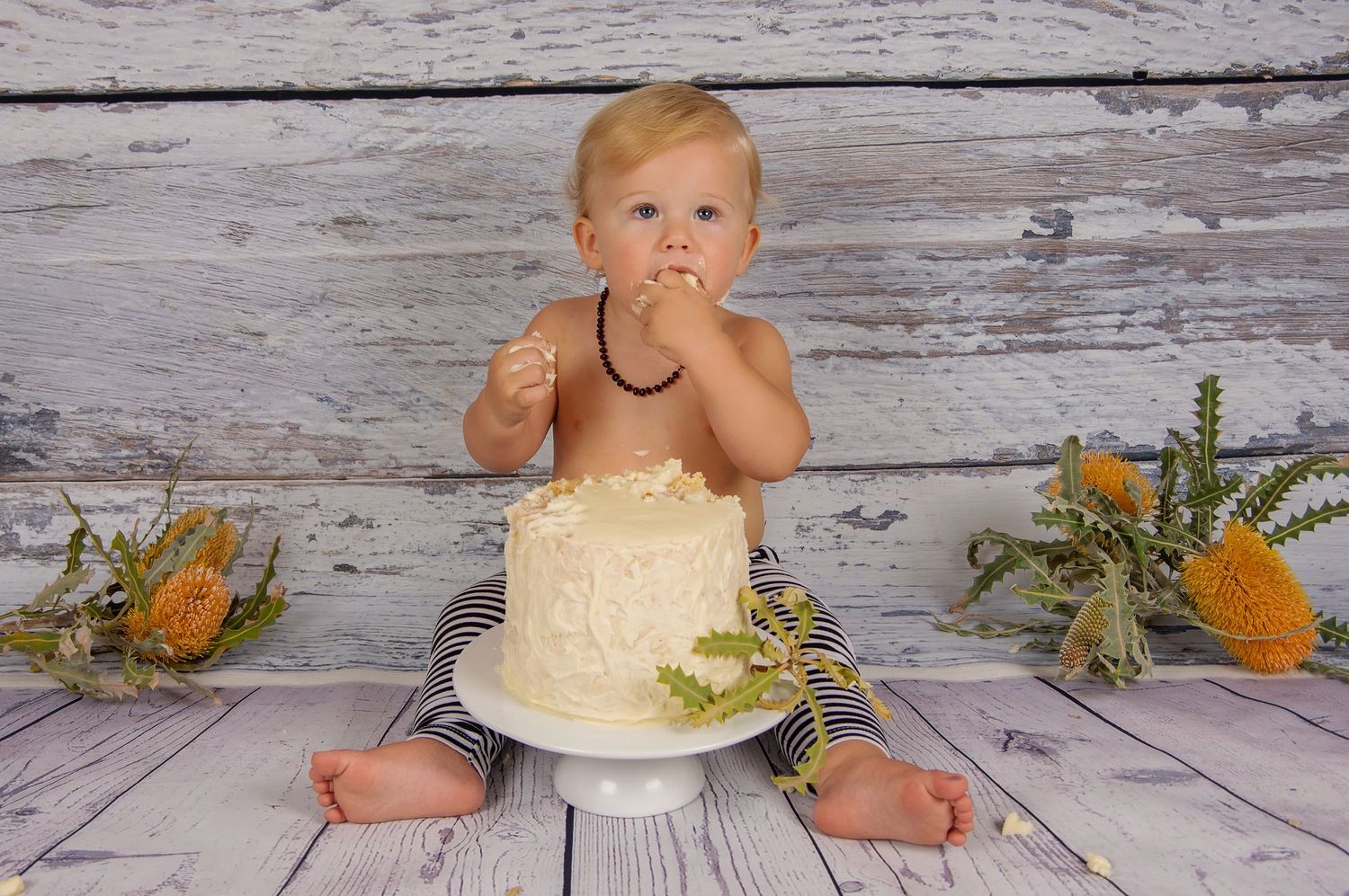 blonde baby eating cake on grey backdrop