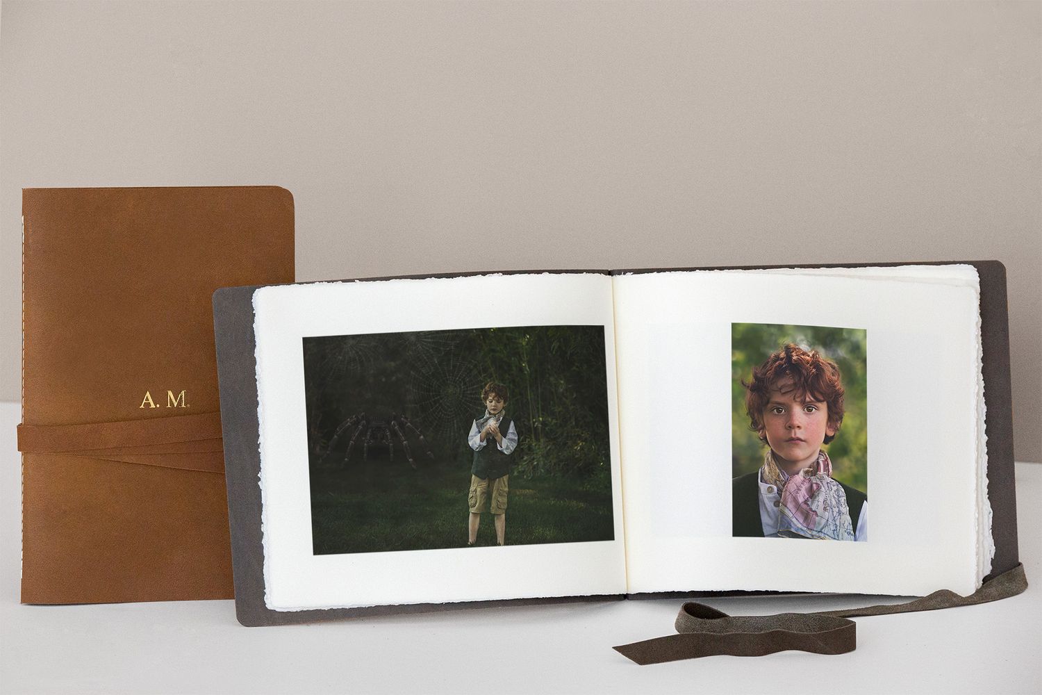 Leather journal and photo album displaying portraits on a white surface.