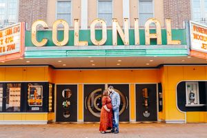 Vintage Colonial theater marquee with orange and green signage on brick building exterior.