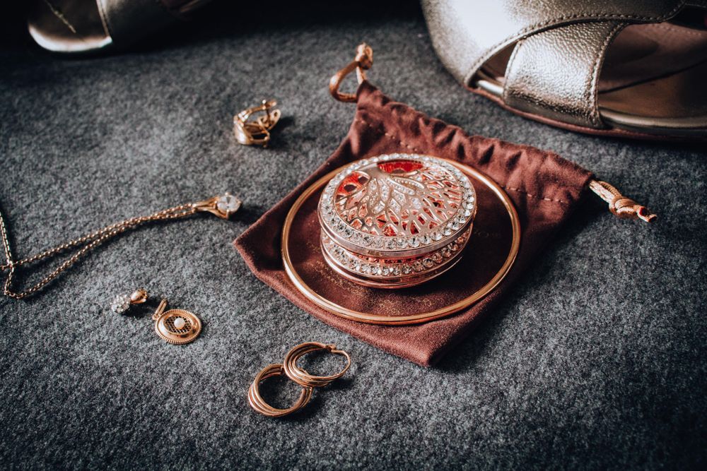Wedding rings and decorative box arranged on dark fabric with elegant details.