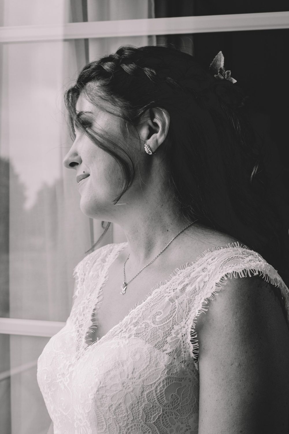 A side profile portrait of a bride in a lace wedding dress with delicate hair accessories.