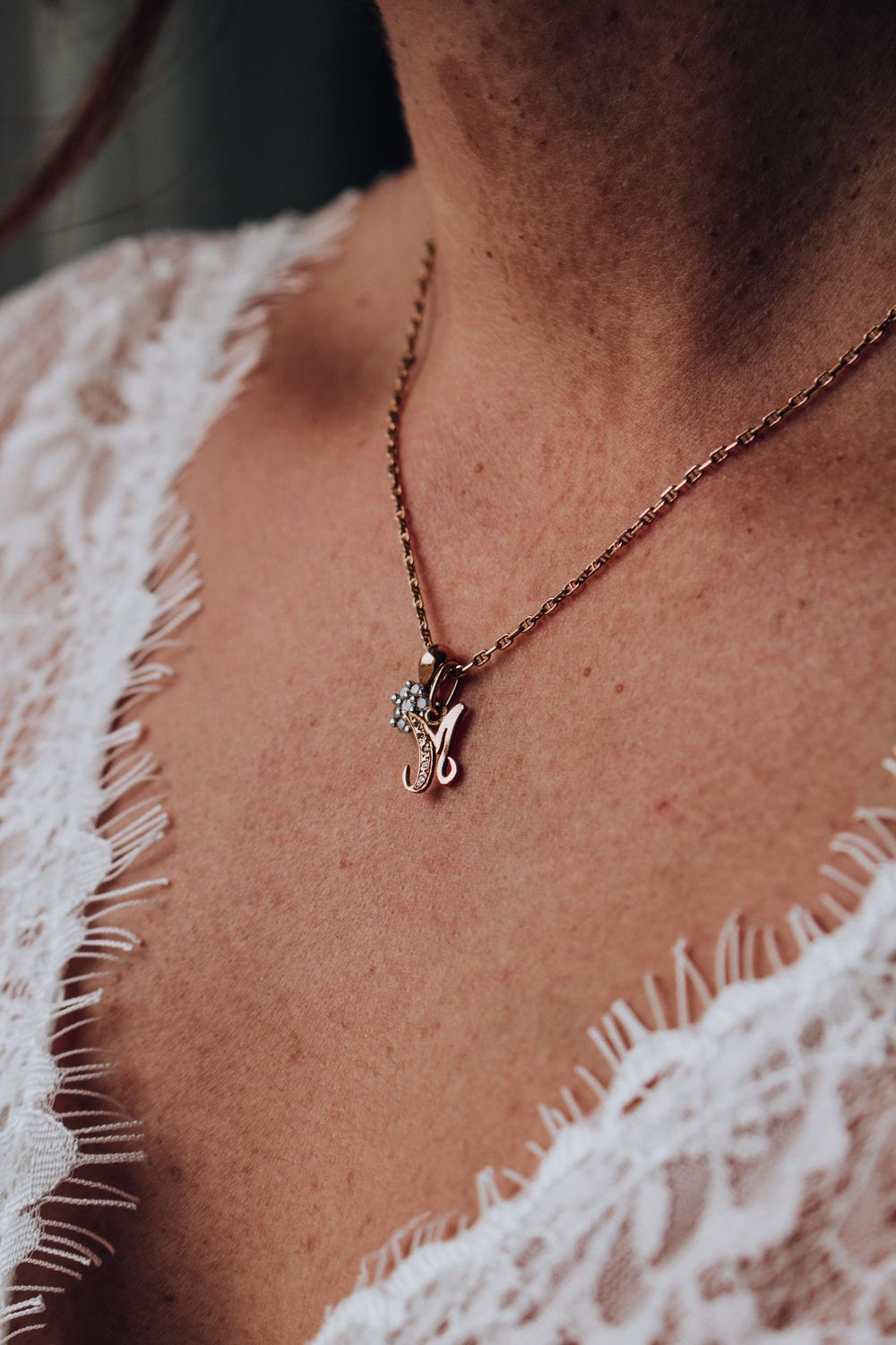 A close-up of a delicate necklace on lace wedding dress details.