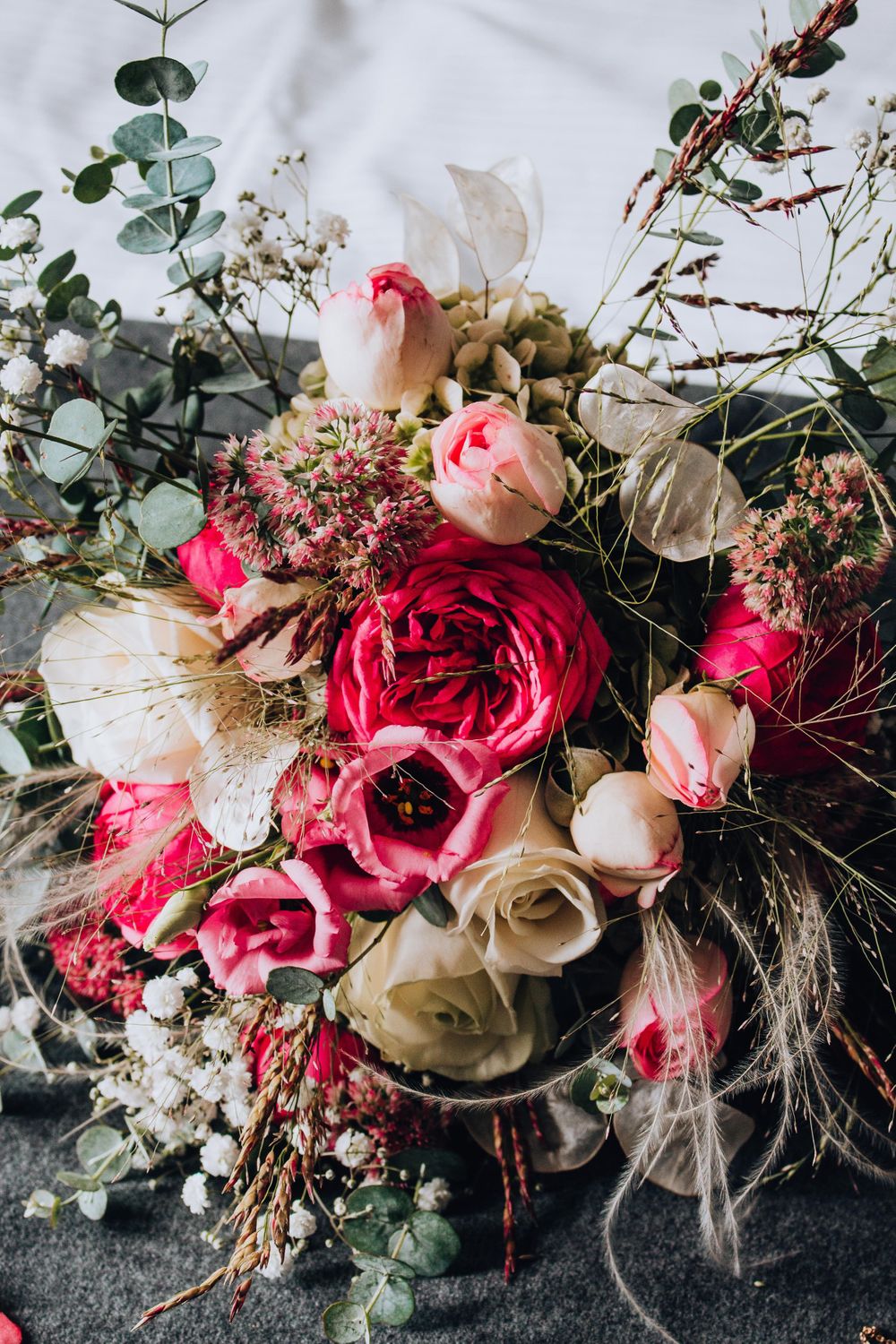 Stunning wedding bouquet with pink and white roses, eucalyptus leaves, and delicate dried flowers.
