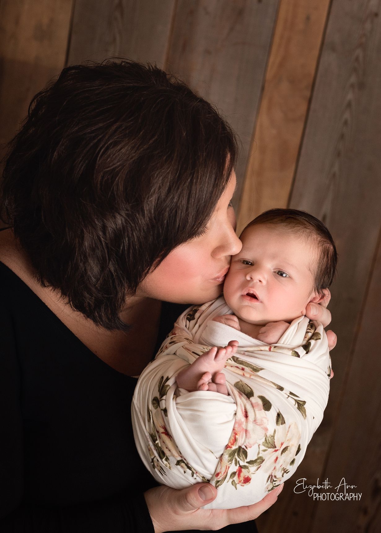 Beautiful mother kissing her newborn daughter, floral wrap and barnwood backdrop; Elizabeth Ann Photography Wisconsin