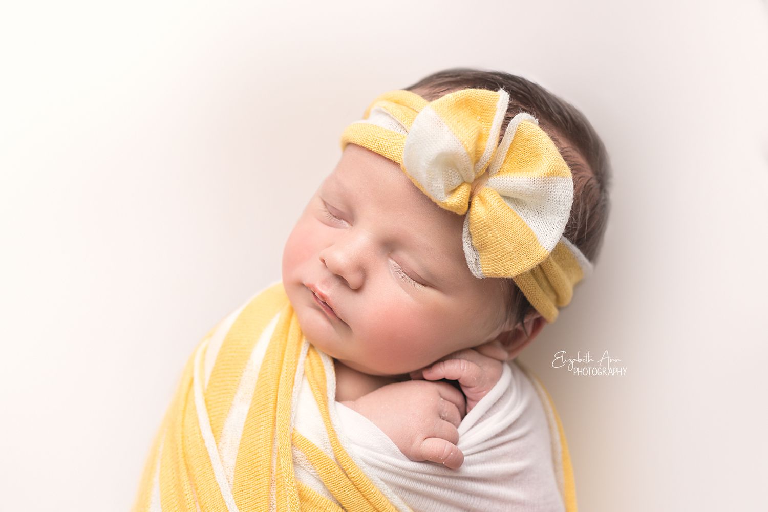Newborn baby girl wearing yellow and white striped headband and wrap; Elizabeth Ann Photography Wisconsin