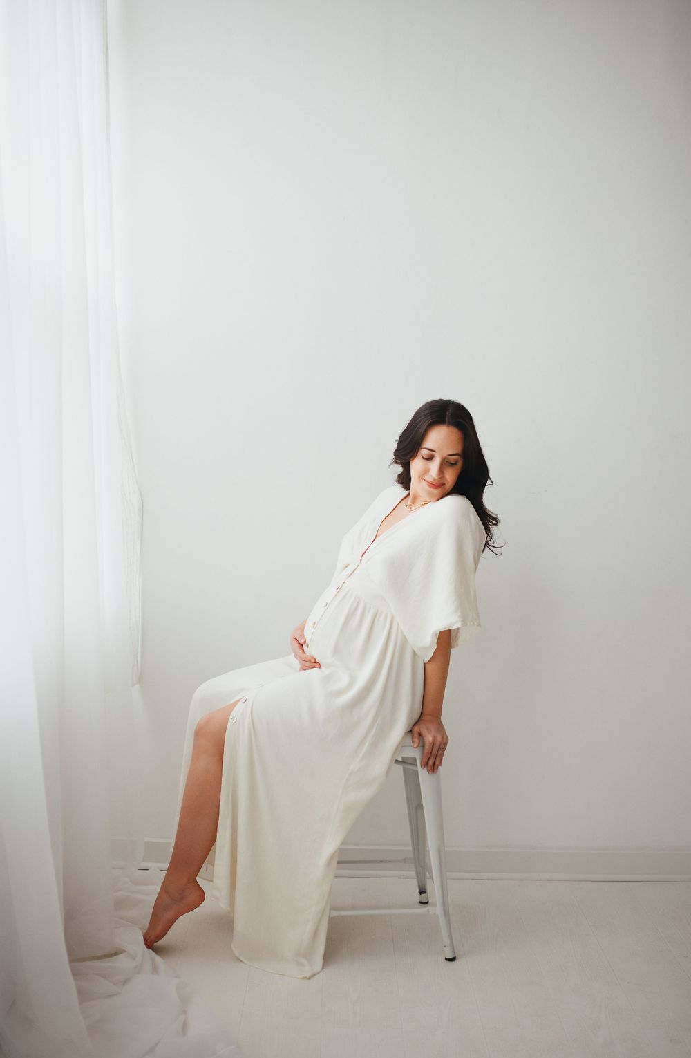 A figure in a flowing white dress poses gracefully against a minimalist white backdrop in a photo series.