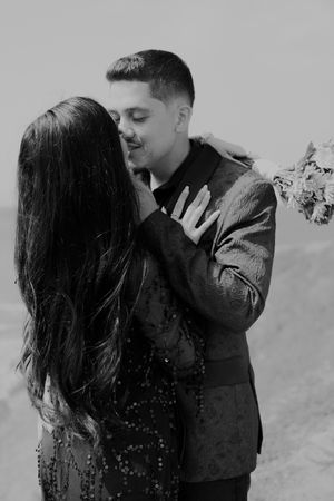 Black and white portrait of couple sharing intimate moments outdoors.