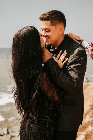 Joyful couple embracing and laughing together by the ocean.