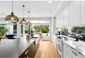 Luxurious white kitchen with gold pendant lights and marble countertops.