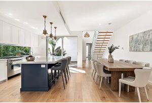 Contemporary dining space with navy island and wooden table setting.