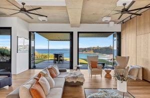 Coastal living room with panoramic ocean views, wooden floors, and modern furnishings.