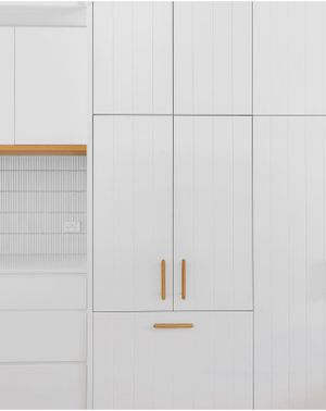 Minimalist white cabinet doors with brass handles and vertical paneling.