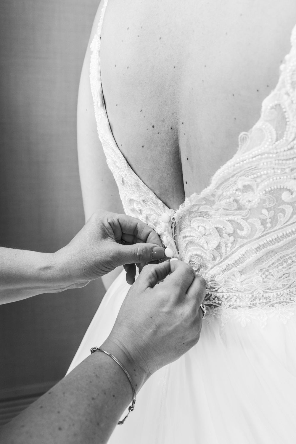 Close-up sequence showing delicate lacing and buttons being fastened on a white wedding dress.