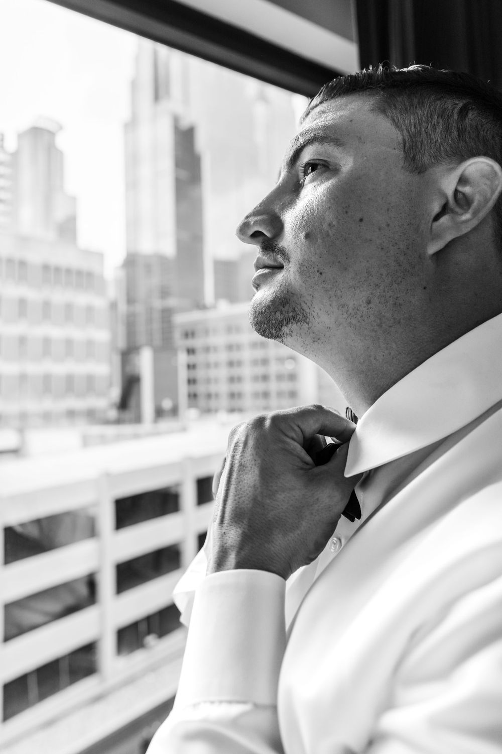 Profile views of person in white formal attire against city backdrop.