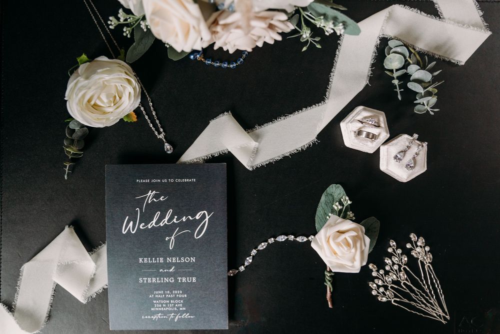 Wedding invitation suite with white roses and delicate details on dark background.