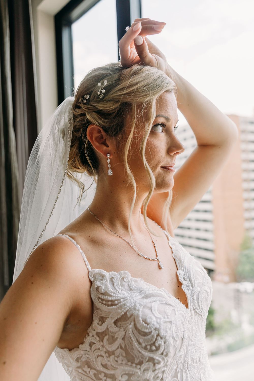 Elegant bridal portrait showing intricate lace details and veil near a window.