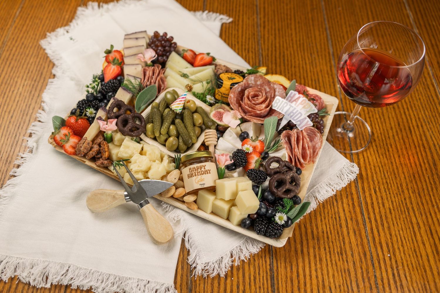 Overhead view of charcuterie board with assorted meats, cheeses, and pickled vegetables served with red wine.