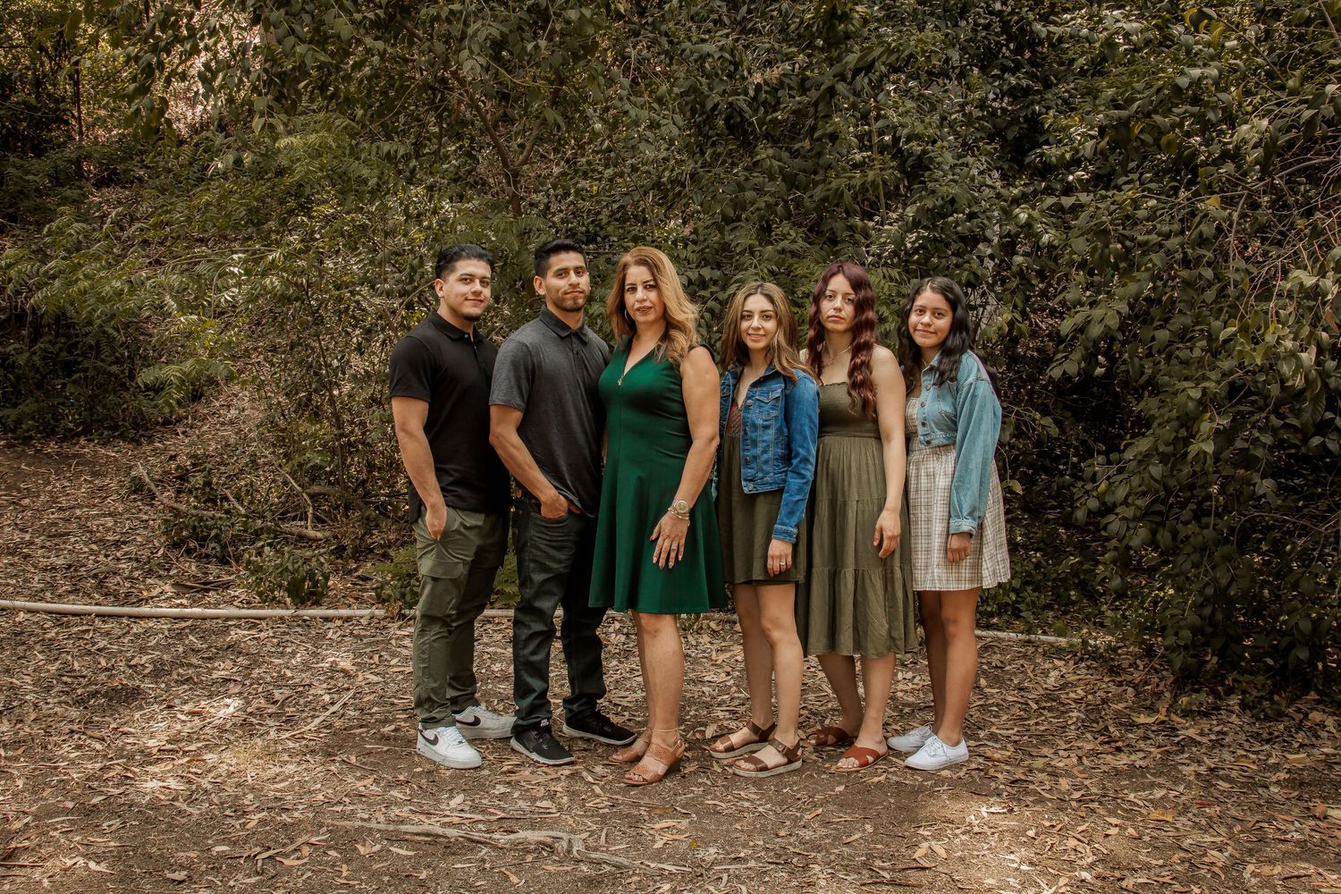 Group of friends standing together on a wooded trail in casual dress attire.