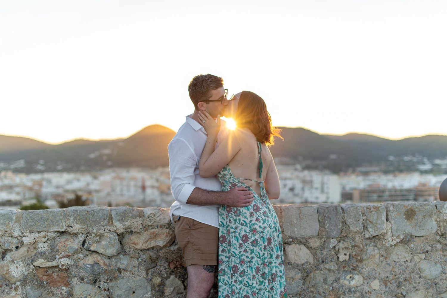 A couple kiss as the setting sun shines behind them at the top of Ibiza's old town