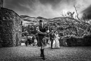Doedelzakspeler leidt het huwelijkskoppel naar het kasteel in Eilean Donan te Schotland