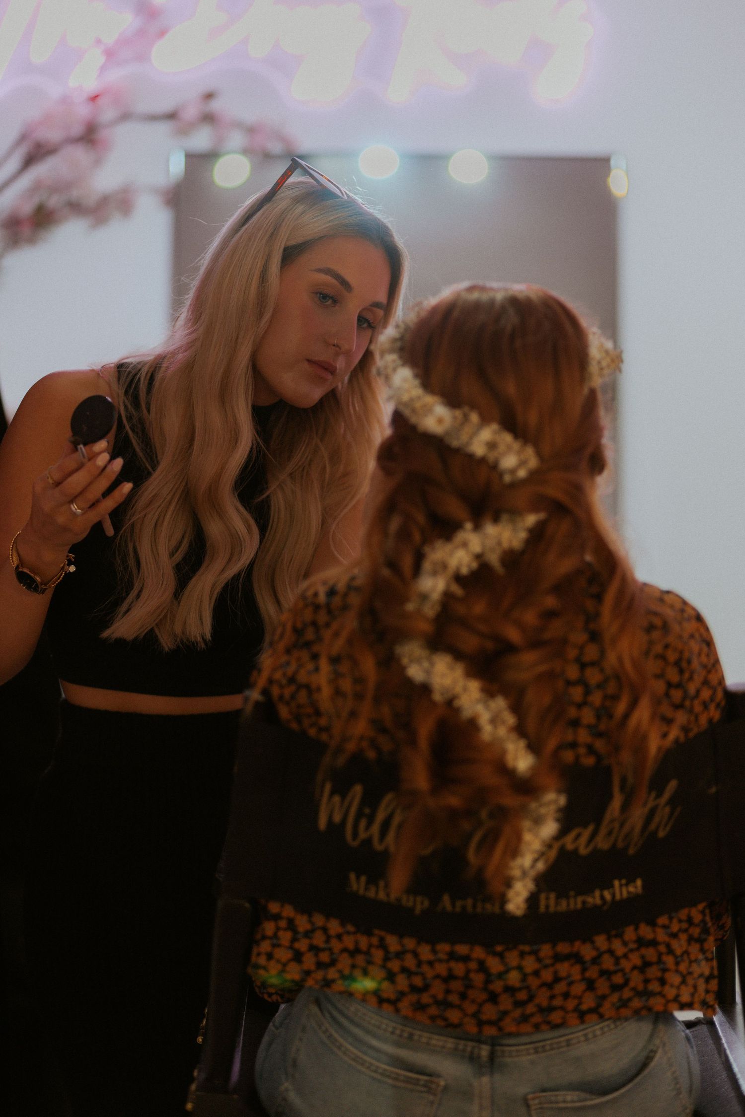 A makeup artist and client having a pre-wedding makeup session with a leopard print jacket in view.