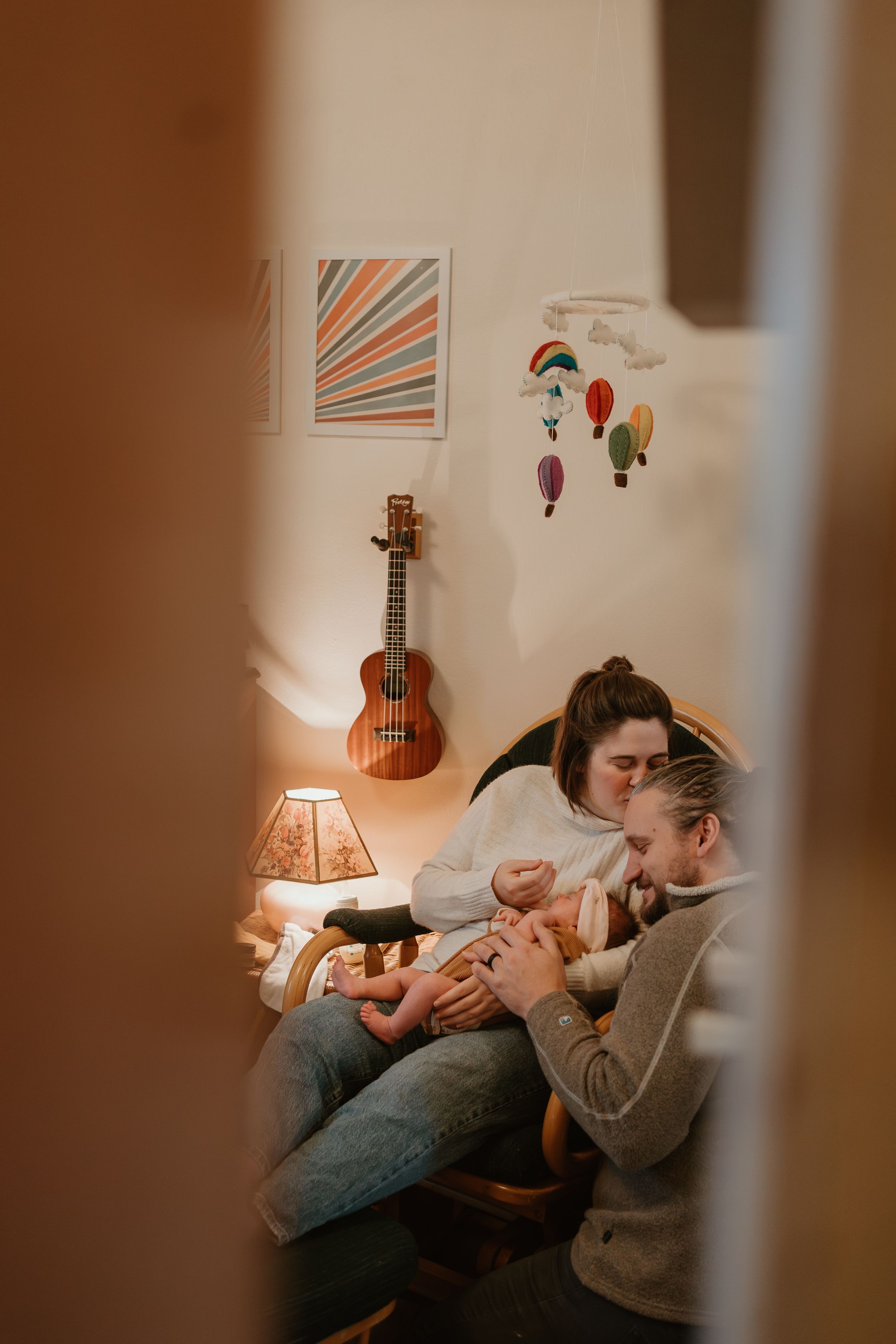 Intimate family moment in cozy room with ukulele and wall art visible.