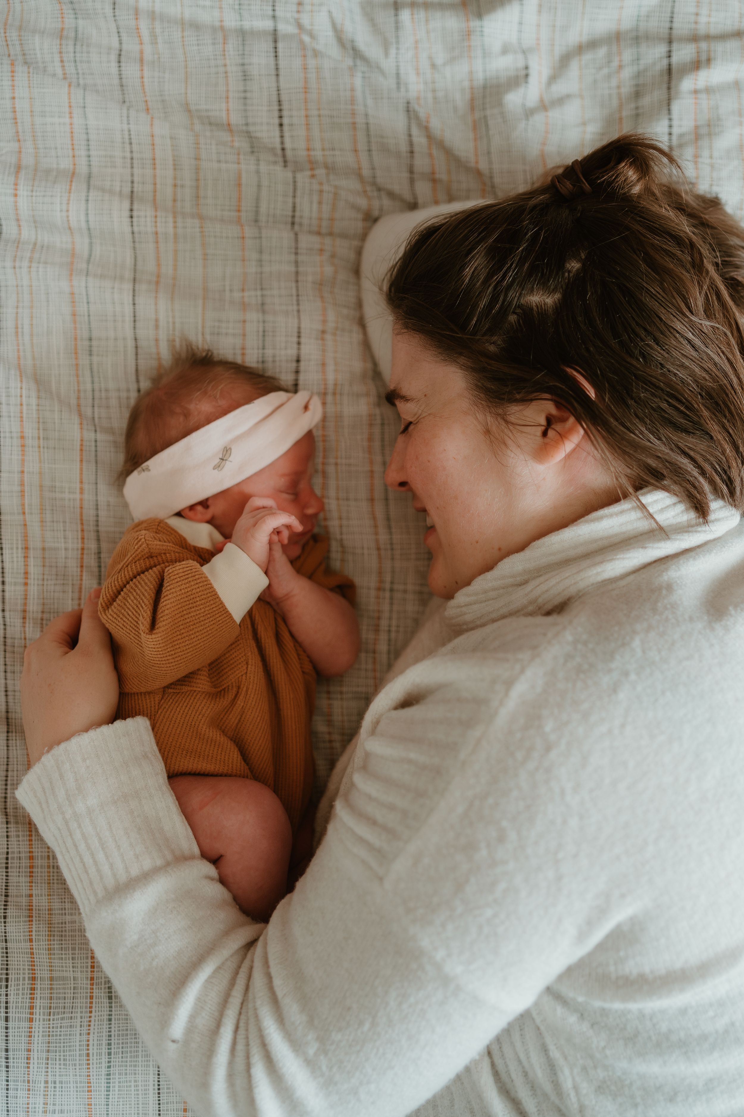 Sweet tender moment of family bonding with newborn baby on white bedding.