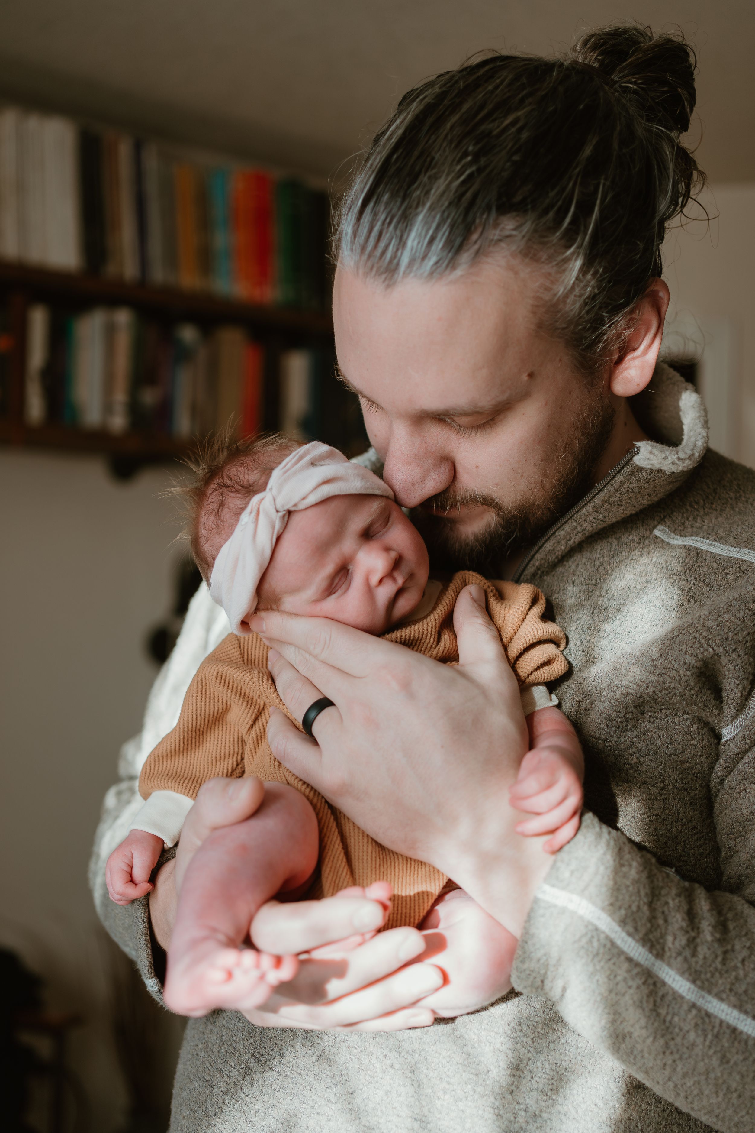 Tender moment between parent and newborn baby in soft indoor lighting.