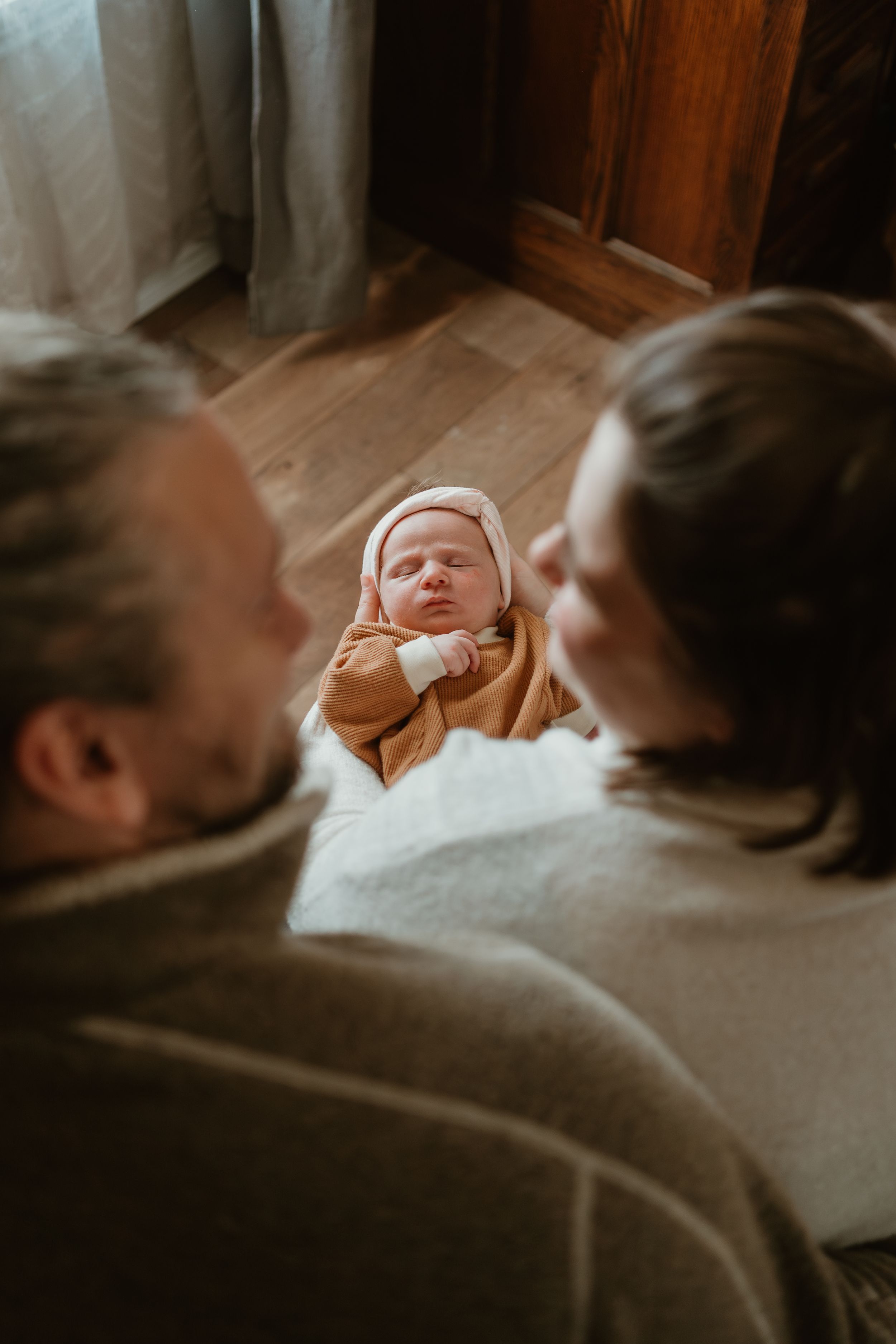 Peaceful moment of family bonding with sleeping newborn on soft white surface.