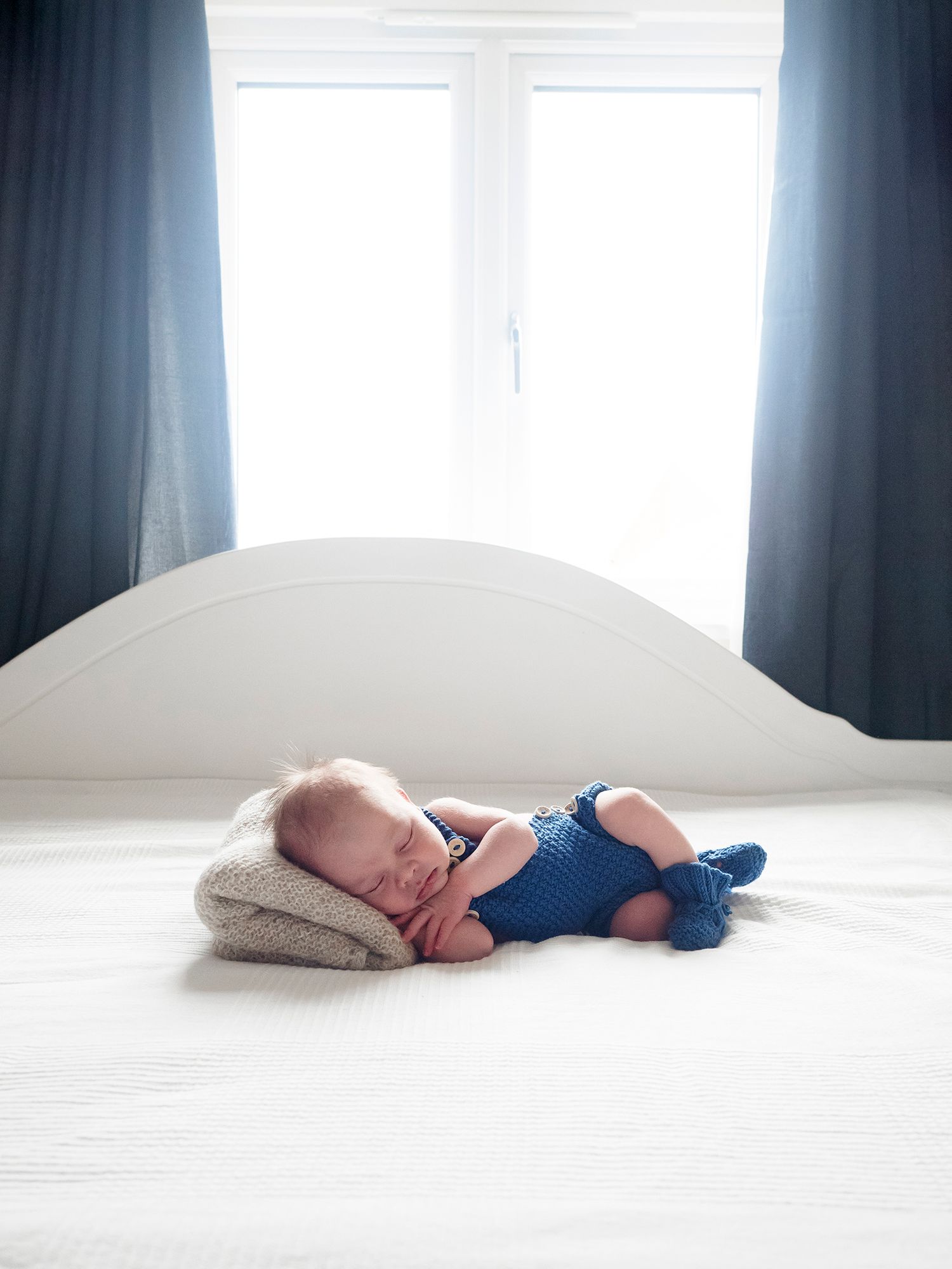 baby sleeping on parents bed in front of window