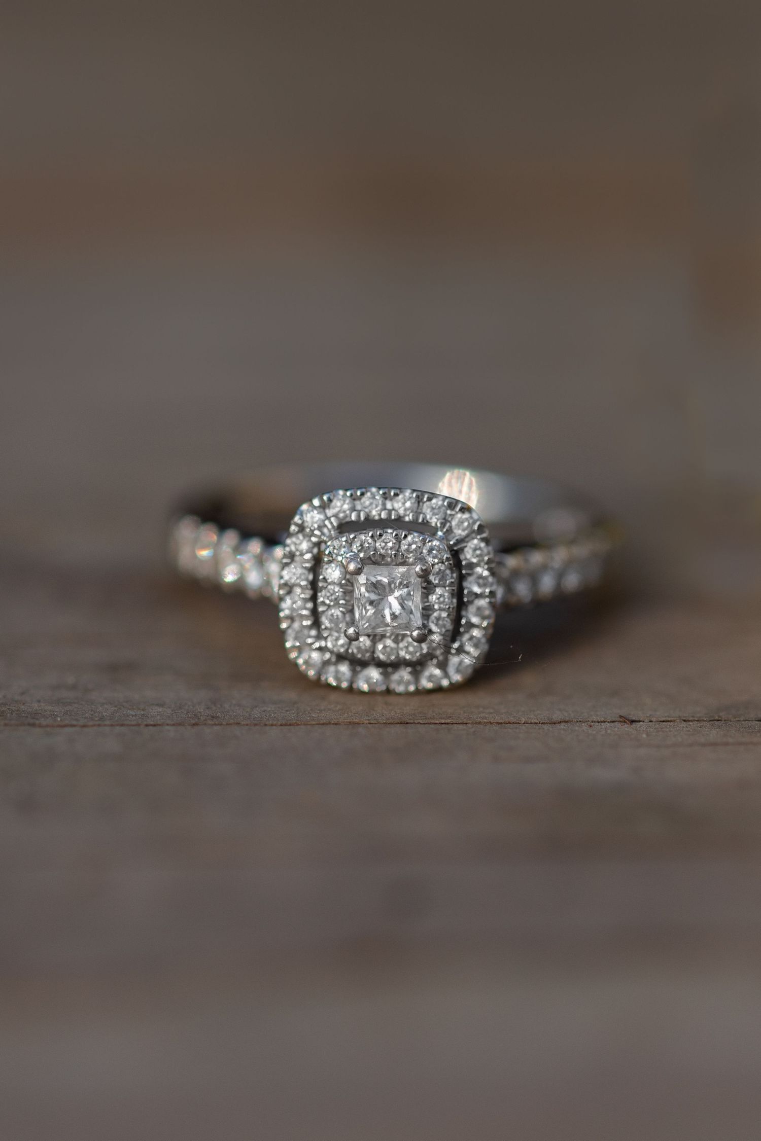 Diamond engagement ring with double halo design photographed on wooden surface.
