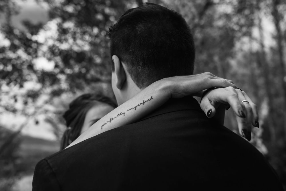 A woman's arms wrap around the shoulders of her groom in intimate black and white wedding image
