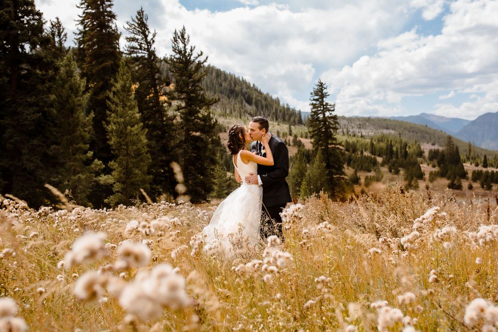 A bride and groom kiss in a golden Colorado field