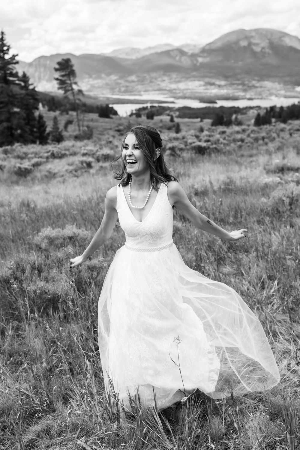 A bride smiles joyfully in a Colorado mountain field black and white wedding photograph