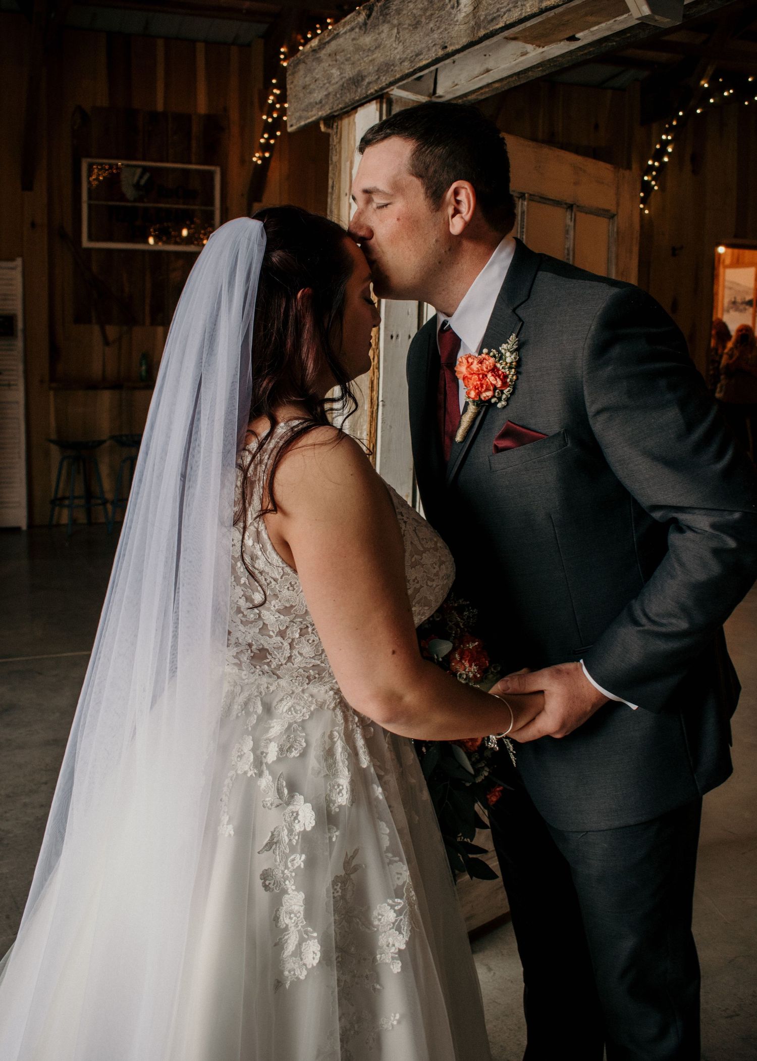 groom kisses bride on forehead during first look