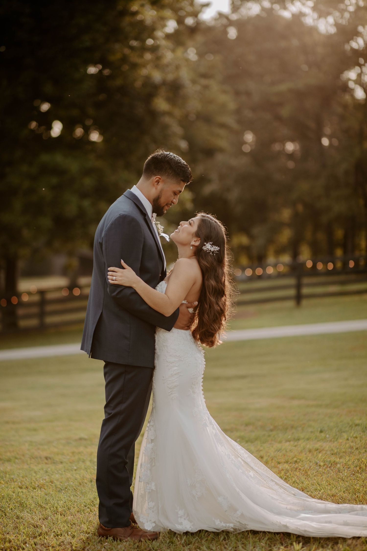 Sunset wedding on a ranch. Couple in wedding attire lean in for a kiss.