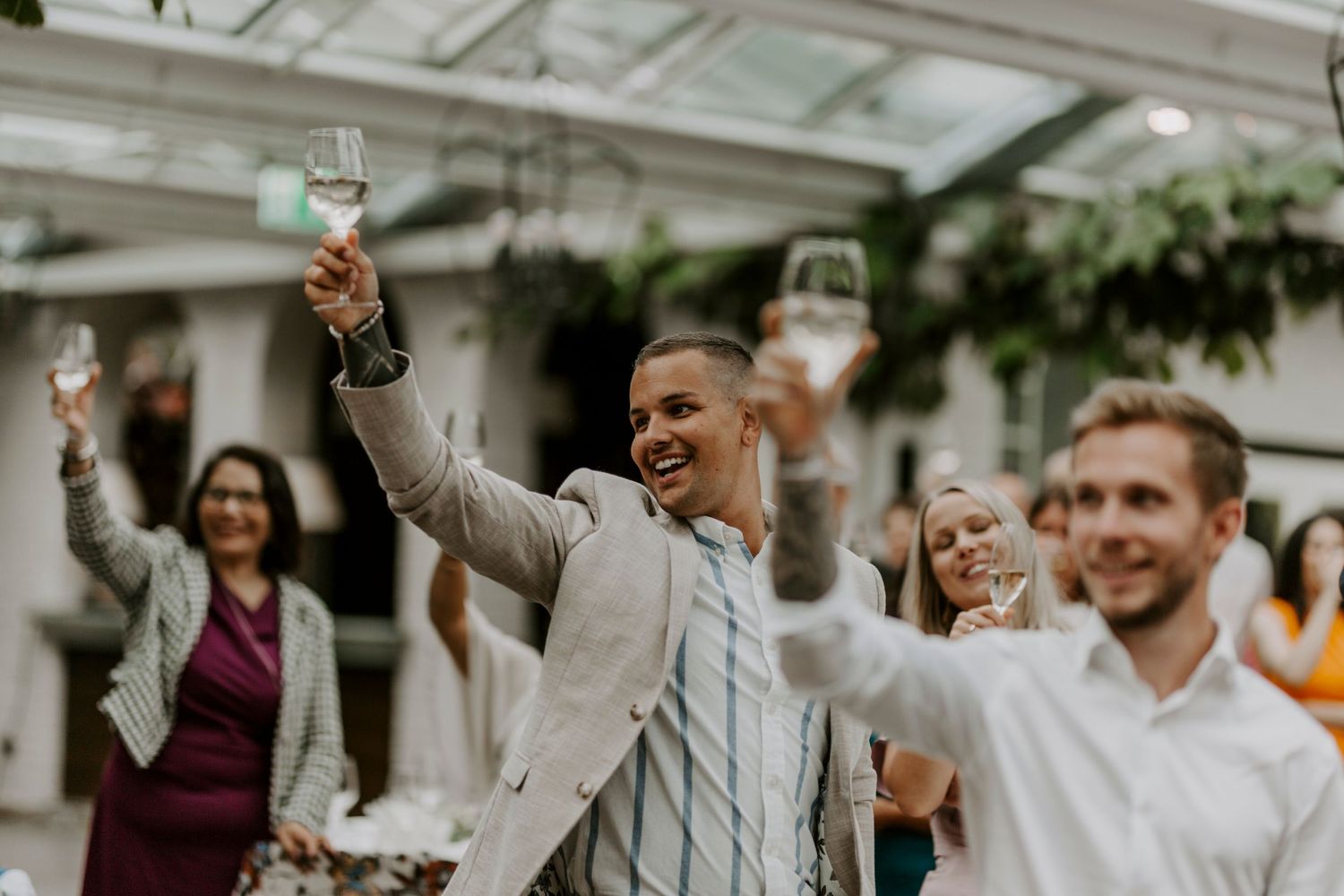 Wedding guests raise their glasses in celebration during an outdoor reception.