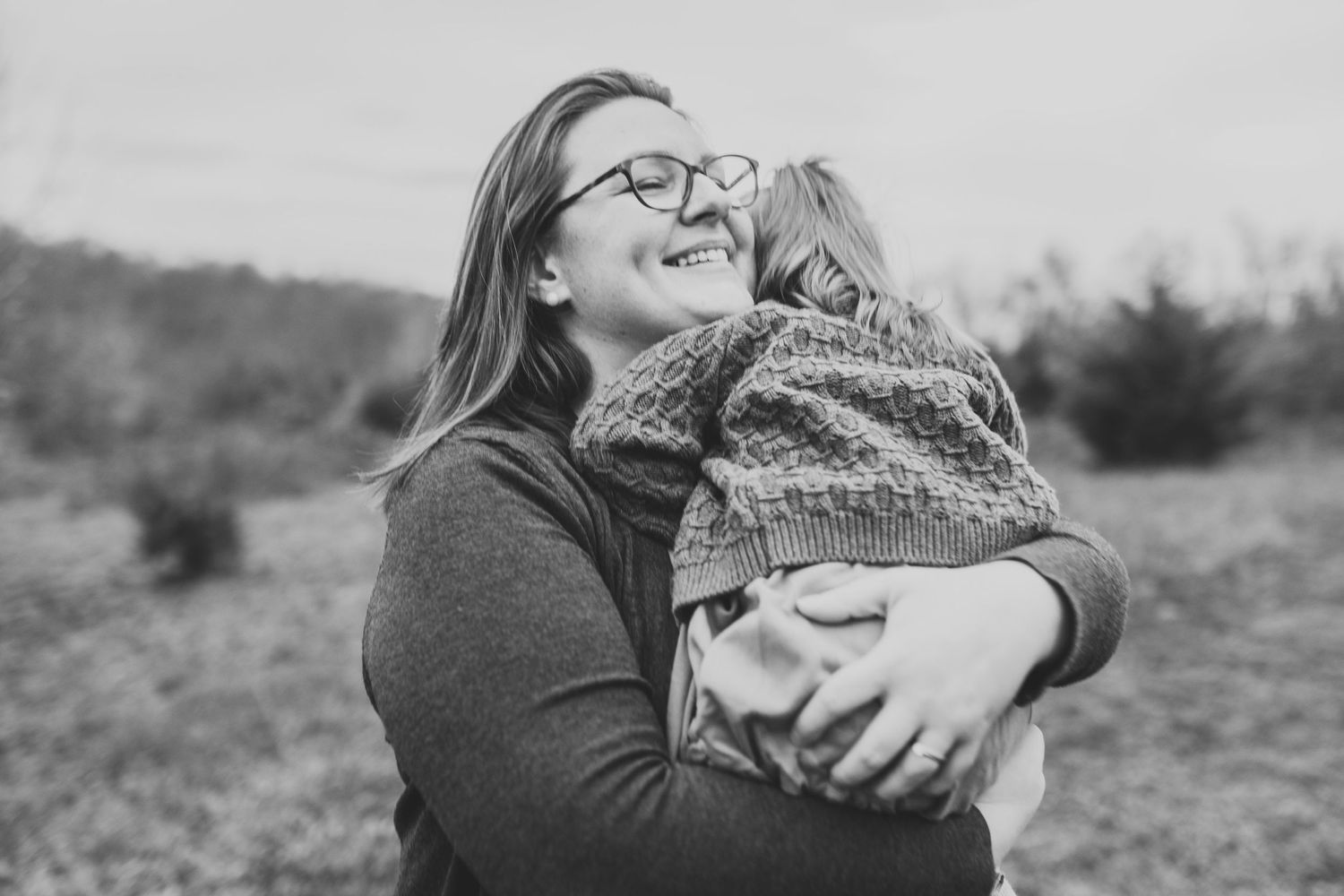 A joyful black and white portrait showing a warm embrace outdoors.