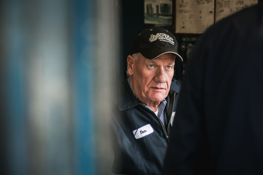 Person wearing a baseball cap in dark lighting with a contemplative expression.