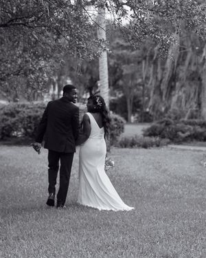Newlywed couple walking together on a garden path in black and white photography.