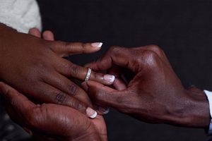 Close up photo of hands exchanging wedding rings during a ceremony.